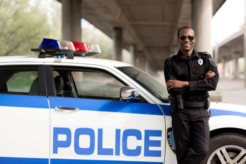 パトカーの前に立つ警察官の画像